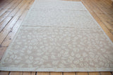 Textured Soumac rug with ivory leaves forming an allover pattern on beige.