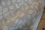 Close-up of hand-woven Soumac carpet texture with ivory and beige leaf design.