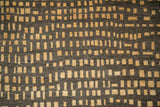 Close-up of hand-knotted abstract rug pile with asymmetric chocolate brown and saffron squares.