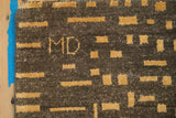 Textured chocolate brown and saffron gold abstract rug with visible MD initials.