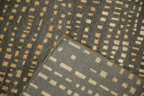 Gold and brown abstract squares on pile, with woven foundation and cord selvage.