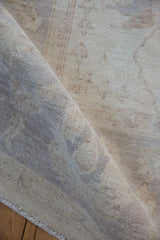 Rolled Peshawar carpet with soft ivory pile, revealing subtle vinery and fringed edge.