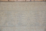 Peshawar carpet pile, showing soft ivory and pale beige hues, subtle palmette motifs, and fringe.