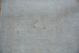 Light brown circular mark on the pale wheat pile of a Peshawar carpet.