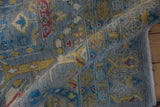 Rolled edge of Pakistani carpet showing pile texture with geometric aqua blue and saffron motifs.