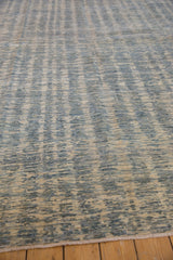 Close-up of contemporary Pakistani rug showcasing intricate striated blue and ivory pattern and fringe.