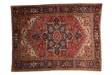 Vintage Persian Heriz carpet with a large-scale geometric medallion in cherry red, navy blue, and emerald green.