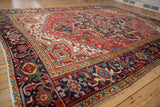 Angled perspective on a vintage Heriz carpet highlighting its intricate navy border and geometric red field.