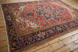 Angled view of a vintage Persian Heriz carpet, displaying its large-scale geometric design and complex borders.