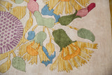 Thick plush pile close-up of Art Deco floral motif with serrated petals and aubergine checker design.