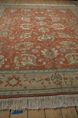 Angled detail of vintage Armenian Sultanabad rug showing copper-terra cotta field, beige border, and fringe.