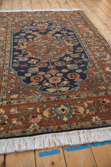 Angled view of a vintage Hamadan rug, showing the detailed floral border and crisp white fringe.