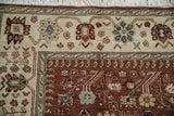 Corner of an Armenian rug showing the detailed ivory floral border and rich copper-red field.