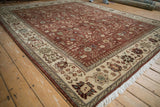 Angled view of a vintage Armenian carpet's intricate ivory border and rich copper floral field.