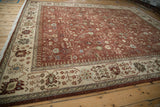 Angled view of the vintage Hamadan design rug's ivory border with pinwheel florals and its copper-red field.