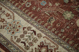 Detail of meandering blossoms and botehs on the vintage rug's ivory border and copper field.