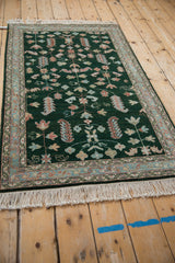 Armenian Hamadan rug corner: deep emerald field, colorful germinating plants, thin vines, patterned border.