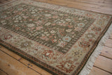Angled view of a vintage Armenian rug's sage green field, lush pile, and floral border.