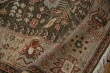 Folded corner of a vintage Armenian rug showing its dense sage pile, floral border, and fringe.