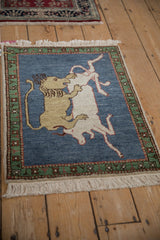 Vintage pictorial Armenian rug: lion and prey on dark blue, emerald green border.