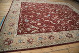 Angled view of the vintage Armenian carpet, highlighting the sand-colored floral border and the wine-red field.