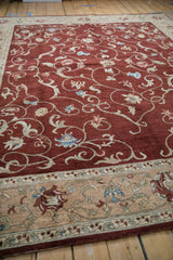 Low angle view across the plush wine-red pile and detailed sand-colored border of the carpet.