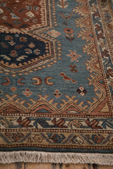 Close-up of a stylized bird motif and meandering vine border on a vintage Armenian rug.