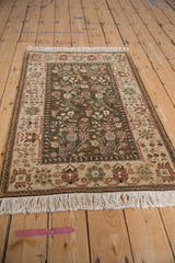Vintage Armenian Hamadan rug at an angle, with a lush olive floral field and soft ivory fringe.