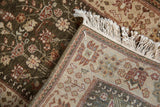 A folded corner showing the hand-knotted back, selvage, and plush olive pile.