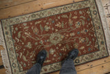A vintage Armenian Lilihan rug with a copper field and floral vinery, shown on a wood floor for scale.