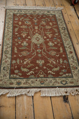 Angled perspective of the vintage Armenian rug's deep copper field and intricate floral vinery.