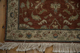 Corner of a vintage Armenian rug with a floral border, deep copper field, and clean ivory fringe.