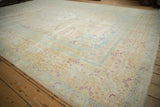 Angled corner view of a distressed rug with magenta floral sprays over powder blue and ivory borders.