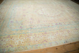 Angled view of a distressed Bulgarian carpet with a time-softened palette of ivory, powder blue, and magenta florals.