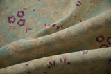 Soft folds of a vintage Bulgarian carpet showing its low-pile texture and magenta floral motifs.
