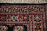 Finely woven corner of a Bokhara rug with geometric gul medallions and ivory fringe.