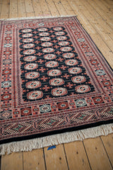 Angled view of a vintage Bokhara rug's lustrous wool pile and repeating geometric gul pattern.