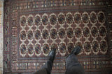A person's view of the plush wool pile and repeating gul medallions on a vintage Bokhara rug.