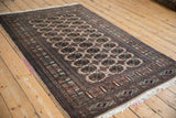 Angled view of a vintage fine Bokhara rug, showcasing its repeating geometric gul pattern and intricate borders.