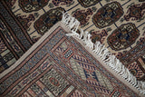 Folded corner of a vintage Bokhara rug showing the hand-knotted construction, secure selvage, and fringe.