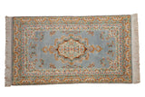 Vintage Indian Kerman design rug with dusty blue field, floral medallion, and Safavid dragon border.