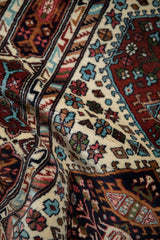 Draped view of vintage Indian Caucasian rug with geometric blossomed plants and starbursts.