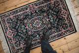 Black field vintage Pakistani Savonnerie rug, oval medallion and red, turquoise floral details underfoot.