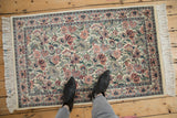 Vintage Pakistani Arts and Crafts rug corner: ivory, red, blue floral design with fringe.
