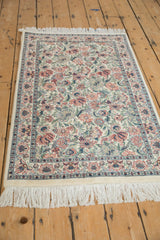 Ivory Pakistani Arts and Crafts rug corner with dense red, blue, green floral pattern and intricate border.