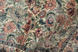 Plush pile of the vintage Pakistani Arts and Crafts rug, featuring ivory, green, and red flowers.