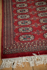 Vintage Bokhara rug detail: cherry red geometric gul, nuanced plant borders, white fringe.