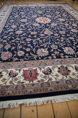 Vintage Isfahan rug's ivory border with blush palmettes, navy field vinery, and fringe.
