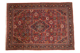 Vintage Mahal carpet with a navy shield medallion on a rust red field of colorful floral and geometric palmettes.