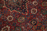 The vintage Mahal carpet's dense floral palmettes in varied shades of brick red, navy, and green.